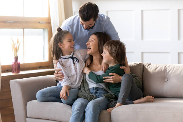 Happy young family with kids relax at home Happy young Caucasian family renters with two small kids sit rest on couch in cozy living room. Smiling parents with little children relax on sofa enjoy weekend in new renovated design home together. father holding son stock pictures, royalty-free photos & images