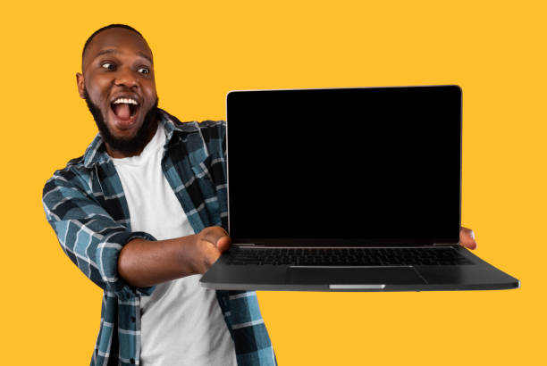 istock Excited Black Man Showing Laptop Empty Screen Over Yellow Background 1309039475
