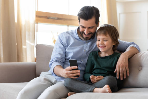 istock Happy dad and little son relax at home using cellphone 1309040269