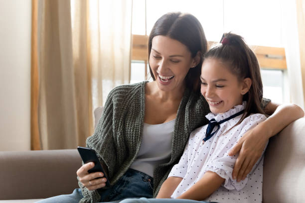istock Smiling young mother and daughter have fun using smartphone 1309040273