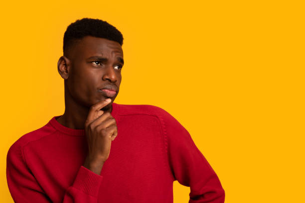 istock Doubtful Young Black Man Looking Aside At Copy Space With Curiousity 1309041043
