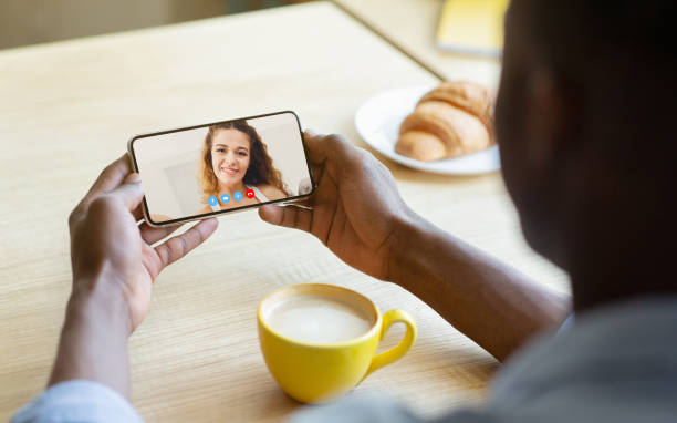istock Young man having online video conference with his girlfriend on mobile phone while drinking coffee at cafe 1309041617