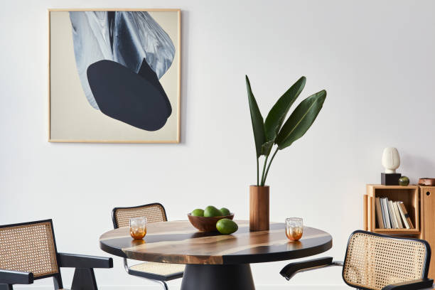 istock Stylish composition of dining room interior with design table, modern chairs, decoration, tropical leaf in vase, fruits, abstract mock up paintings and elegant accessories in home decor. Template. 1309043134