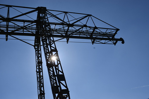 A green crane gracefully suspended against a clear sky, its slender silhouette cutting through the air, symbolizing the breakthrough of industrialism