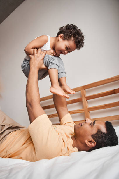 istock Father playing with his funny son while laying at the bed at home 1309045072