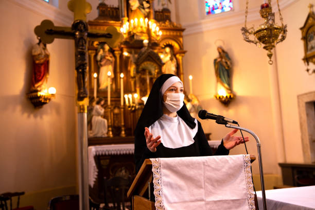 istock Nun reading Holy Bible in Roman Catholic lifting her hands. 1309045429