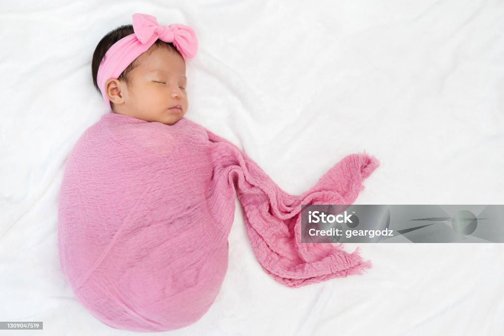 newborn baby sleep in cloth wrap blanket on a bed newborn baby sleep in pink cloth wrap blanket on a bed Baby Blanket Stock Photo