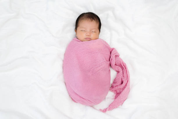 newborn baby sleep in cloth wrap blanket on a bed