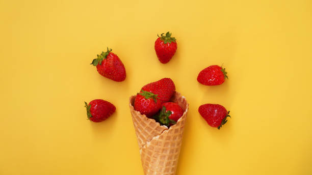 istock Ice cream cone with strawberries on a yellow background 1309047977