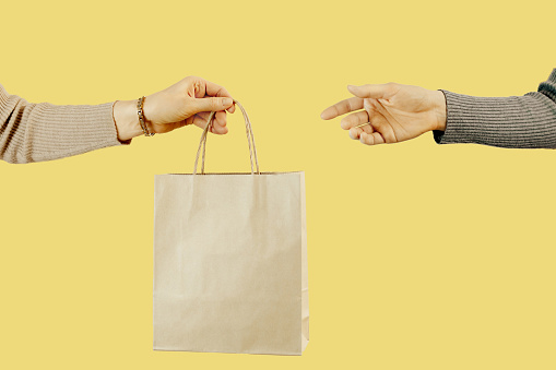 El enfoque selecto de una mano de los woomen es pasar una bolsa de papel artesanal a la otra mano. Concepto de tiendas de segunda mano, reventa, segunda mano. photo
