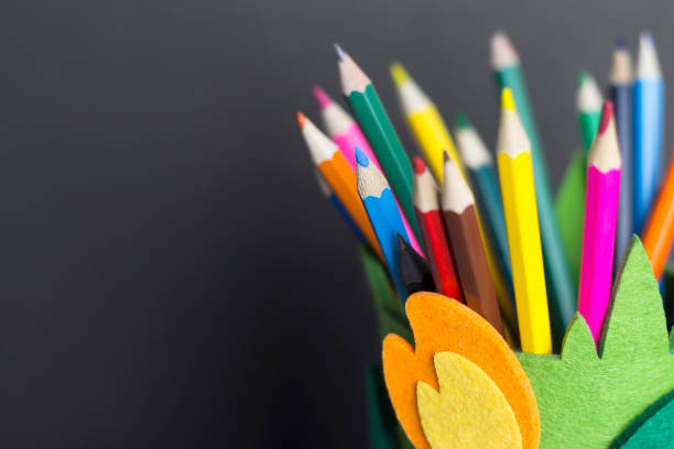 Colored pencils in a textile stand on a black background. DIY pencil holder.