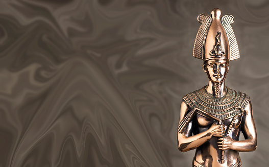 Statuette of the Egyptian pharaoh Tutankhamun on a brown background.