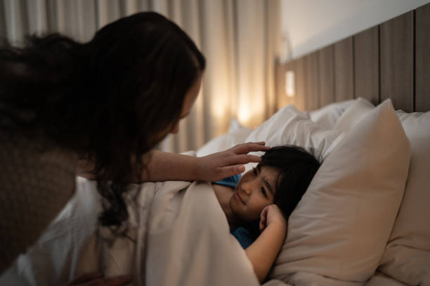 mãe enfiando filha na cama à noite - bedtime - fotografias e filmes do acervo