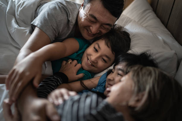 istock Happy family embracing while lying together in bed 1309054082