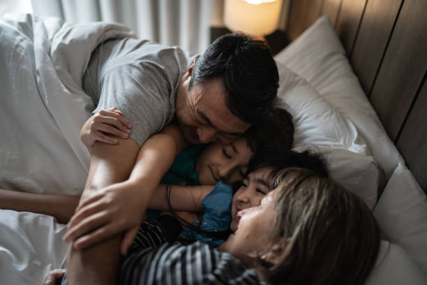 istock Happy family embracing while lying together in bed 1309054159