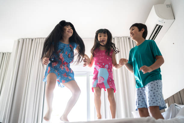 istock Happy siblings jumping on the bed at home 1309054666