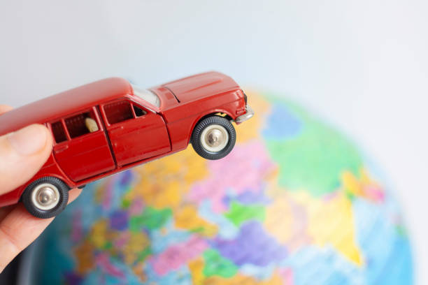 istock Toy car in hand drives around the globe 1309055772