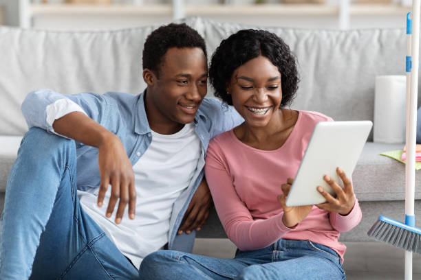 istock Smiling black lovers with digital tablet in living room 1309055795