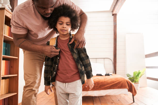 istock Father helping to his little son putting on his backpack while going to school 1309057314