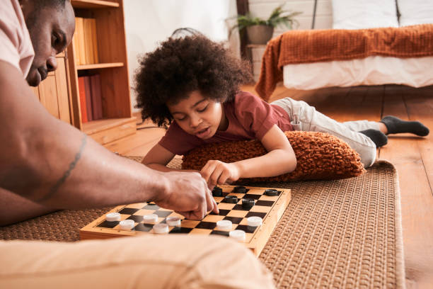 istock Careful father and his curly son playing checkers 1309057323