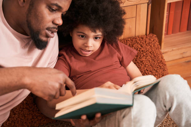 istock Boy is listening while his father reading book to him with interest 1309057333