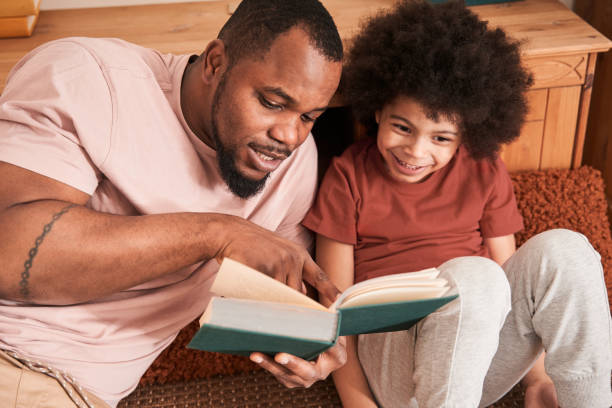 istock Family reading book while sitting together at the floor 1309057336