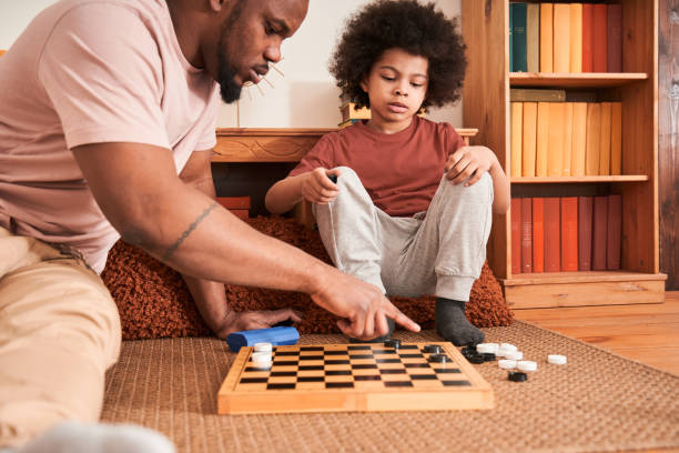 istock Careful father and his curly son playing checkers 1309057339