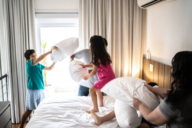 familia que tiene peleas de almohadas en casa - bed couple pillow fight men fotografías e imágenes de stock