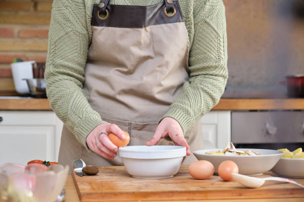 istock Unrecognizable young woman cracking or breaking an egg. Cooking time. 1309059180