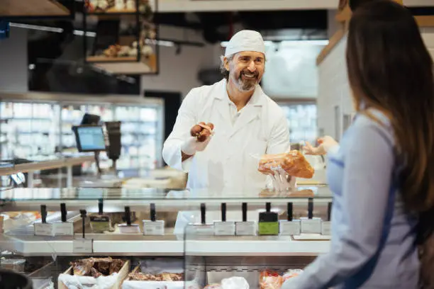 Female customer choosing meat from deli counter in supermarket