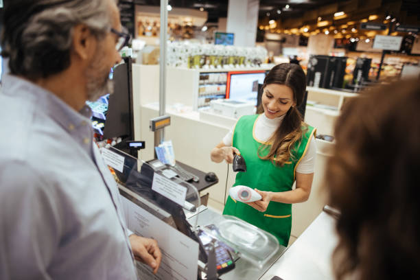 jovens mulheres caixa digitalizando produtos com leitor de código de barras para casal maduro - bar code retail bar code reader food - fotografias e filmes do acervo