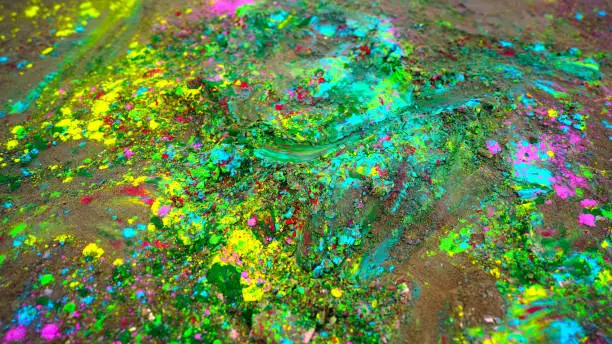 Closeup shot of splashing Gulaal color powder with green colors. Vibrant rainbow colors spreading on ground.