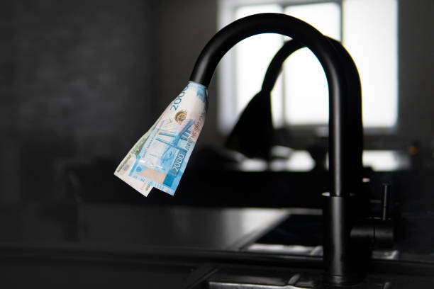 Expensive water supply. The concept of increasing the price of public utilities for the population. Expensive hot and cold water at home. water tap spewing american dollar bills. Expensive water supply. The concept of increasing the price of public utilities for the population. Expensive hot and cold water at home. public utility stock pictures, royalty-free photos & images