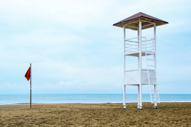 istock Empty lifeguard tower and red storm flag on the beach on a cloudy day 1309067457