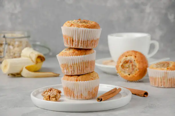 Stack of Banana muffins with oatmeal, walnuts and cinnamon on a white plate on gray concrete background. Healthy dessert
