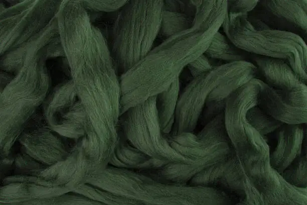Pretty dark olive green merino wool lying in loose stings ready to be used