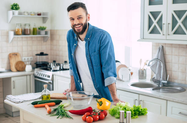 istock Bearded smiling handsome man in the kitchen at home is posing and looking on the camera 1309072964