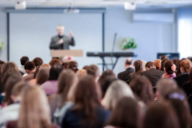 Conference Ideas. Male Lecturer Speaking In Front of the Group of People. Horizontal Image Composition Conference Ideas. Male Lecturer Speaking In Front of the Group of People. Horizontal Image Composition audience photos stock pictures, royalty-free photos & images