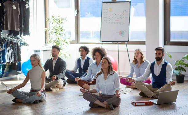 geschäftskollegen meditieren bei der arbeit, sitzen auf dem boden. modern, business, meditationskonzept - personal view stock-fotos und bilder