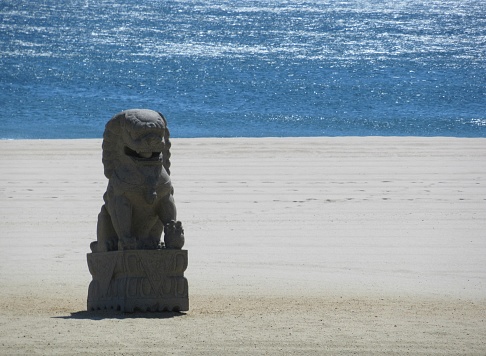 Chinese lion statue on sandy beach