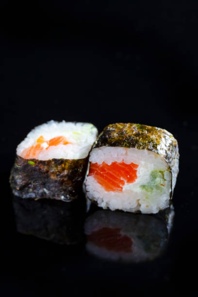 istock Macro Shoot of Two Traditional Sushi Rolls With Red Salmon Together on Black Surface. Vertical Image 1309082409