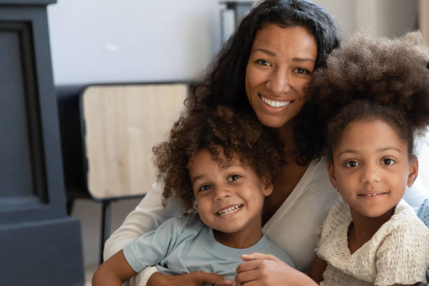 Black female tutor looking at camera posing with beloved pupils Our favorite teacher! Portrait of happy friendly african family millennial mother and two diverse children, talented black female tutor babysitter looking at camera posing with beloved pupils wards mom and sister stock pictures, royalty-free photos & images