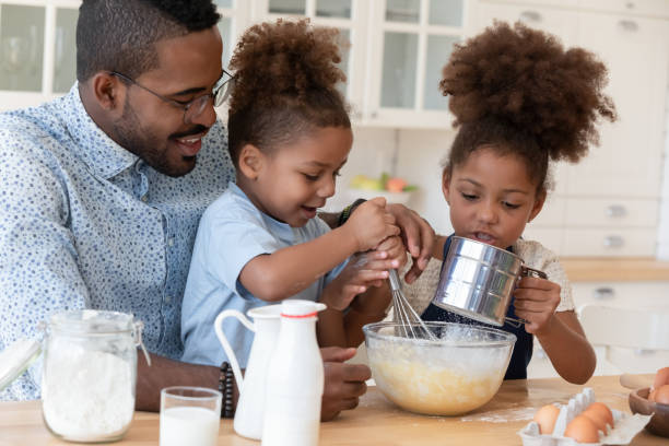 istock Attentive african daddy showing children how to prepare dough 1309082447