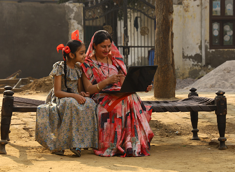 Indian happy rural mother and daughter using laptop in village with a happy smile