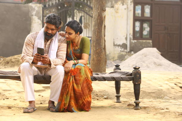 istock Indian happy rural couple using phone in village 1309082557