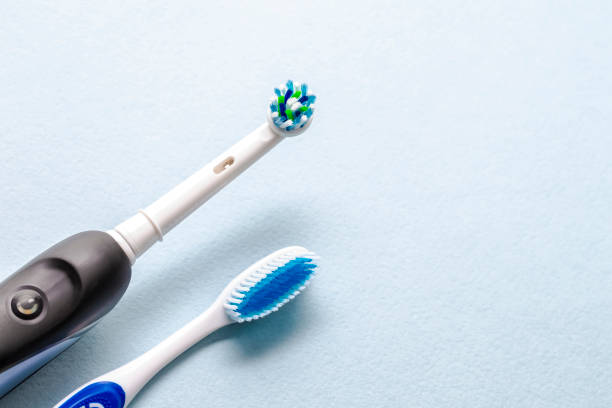 zbliżenie szczotkowania głów profesjonalnej elektrycznej szczoteczki do zębów i ręcznej szczotki na niebieskim tle. obraz poziomy - toothbrush zdjęcia i obrazy z banku zdjęć