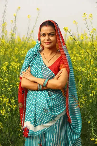 A happy rural woman farmer portrait smiling in the Mustard field showcasing woman empowerment