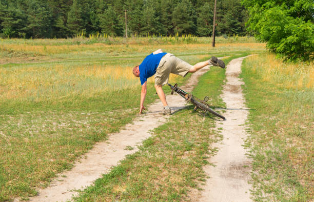 Mature man falling off of an ancient bicycle on a country road in rural village Mala Rublivka in central Ukraine - fotografia de stock