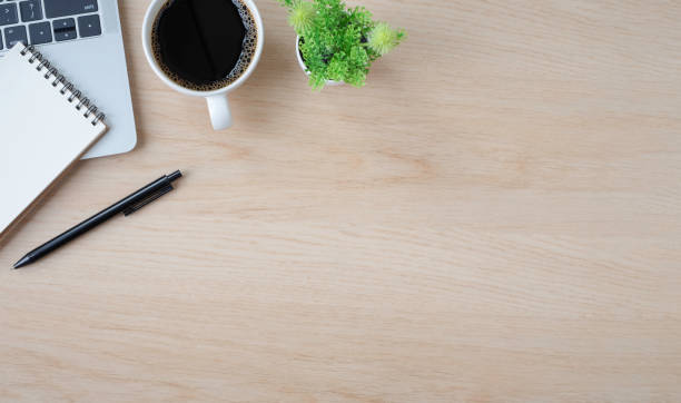 istock Top view above of Wood office desk table with keyboard, notebook and notepad, coffee cup with equipment office supplies. Business and finance concept. Workplace, Flat lay with blank copy space. 1309083626