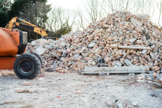 Excavator removes construction waste after building demolition. Building rubble, bricks, stones. Junk, Garbage piled up. Street scene. Recycling industry, rubbish removal, and collection service.